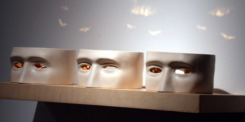 three sculptures of the centre portion of a head on a shelf, eyes are made of glass