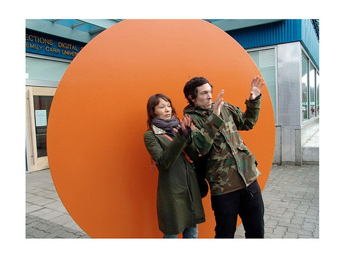 man and woman in front of gold disc