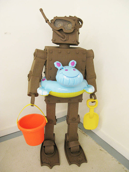 A standing clay sculpture of a robot dressed for the beach