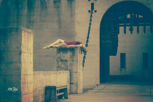 A photo of a dancer lying on a plinth in front of a castle